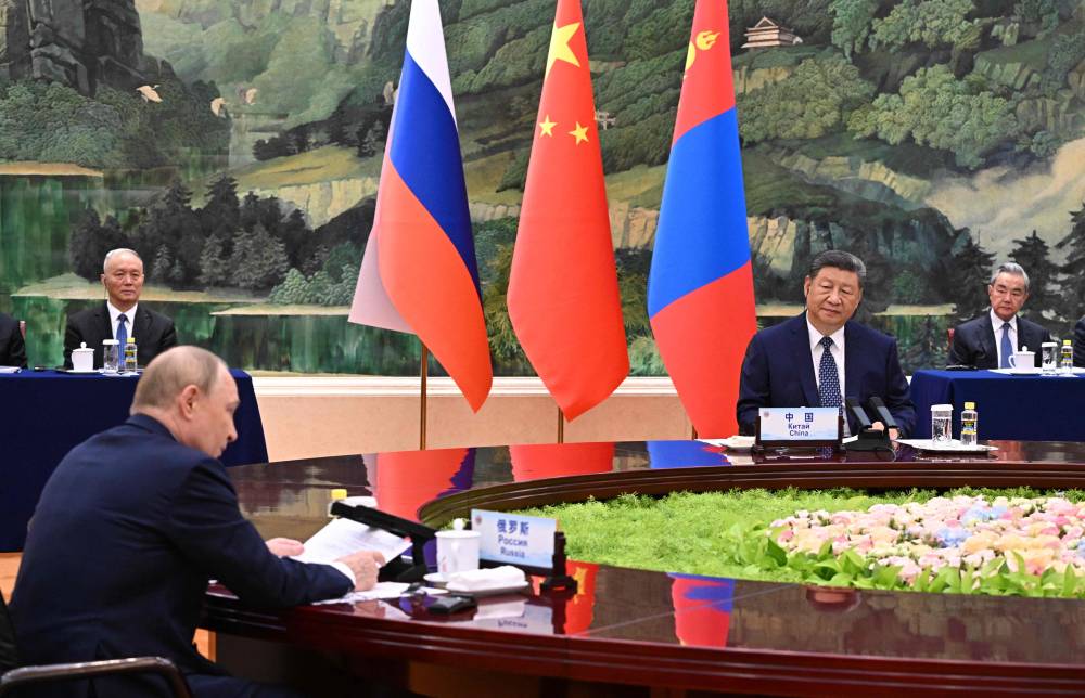 In this pool photograph distributed by the Russian state agency Sputnik, Russia's President Vladimir Putin (L), China's President Xi Jinping (R) and Mongolian President Ukhnaagiin Khurelsukh (not pictured) attend a meeting in Beijing on September 2, 2025. (Photo by Sergey Bobylev / POOL / AFP)