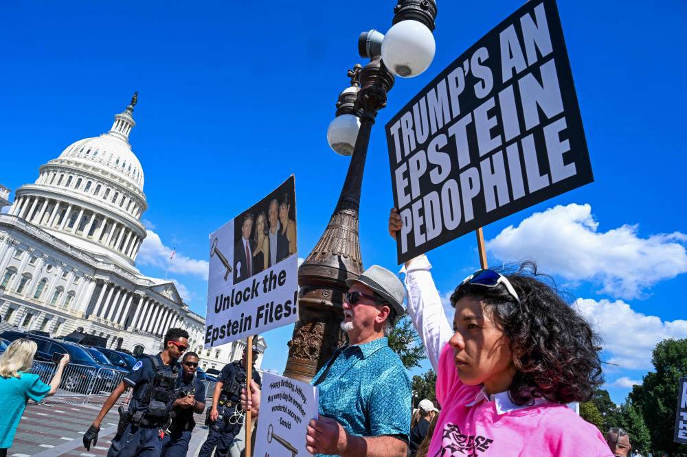 Demonstrators carry signs in support of the victims of sex offender Jeffrey Epstein and his accomplice Ghislaine Maxwell near a press conference held by US representatives outside the U.S. Capitol in Washington, DC on Sept 3, 2025. - (Photo by ROBERTO SCHMIDT / AFP)