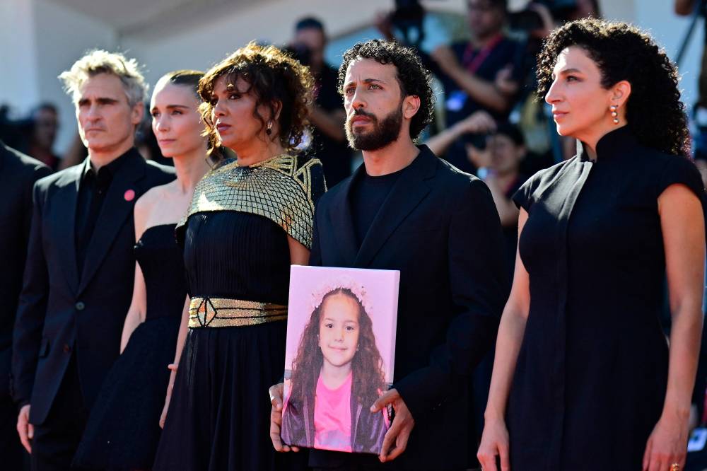 From left: US actor Joaquin Phoenix, US actress Rooney Mara, Tunisian director Kaouther Ben Hania, actor Motaz Malhees and actress Clara Khoury pose with a portrait of late Palestinian girl Hind Rajab during the red carpet for the movie "The Voice of Hind Rajab" presented in competition at the 82nd International Venice Film Festival. - Photo by AFP