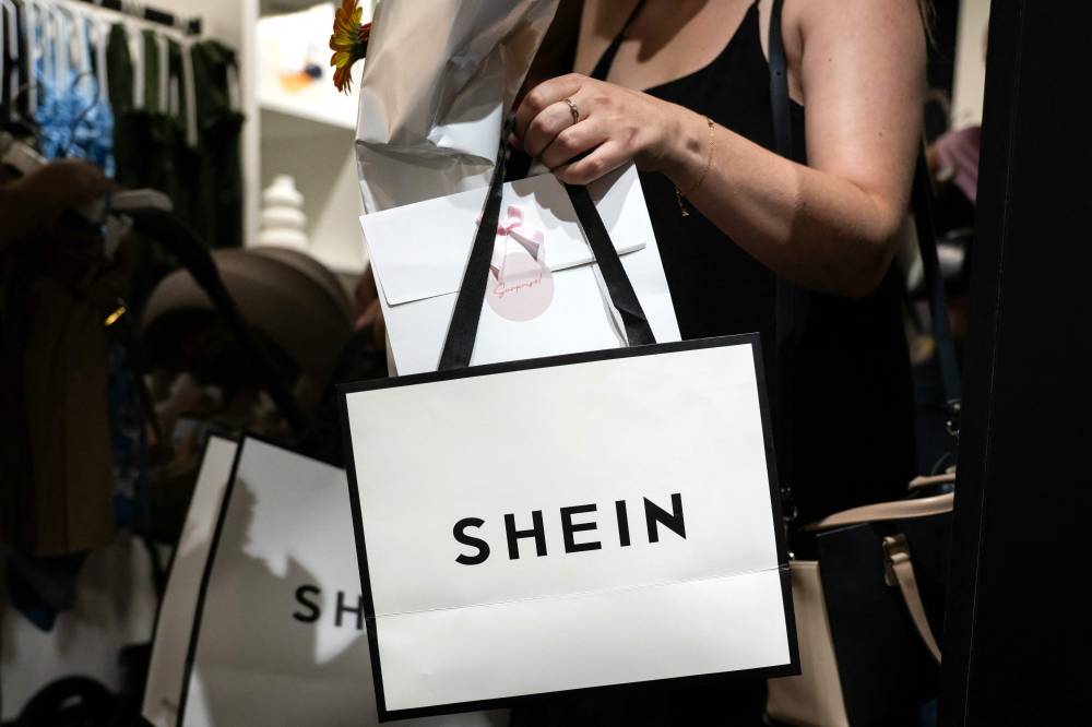 A customer holds her bags as she leaves a pop-up store of the Chinese fast fashion brand Shein, in Dijon on June 26, 2025. - (Photo by ARNAUD FINISTRE / AFP)