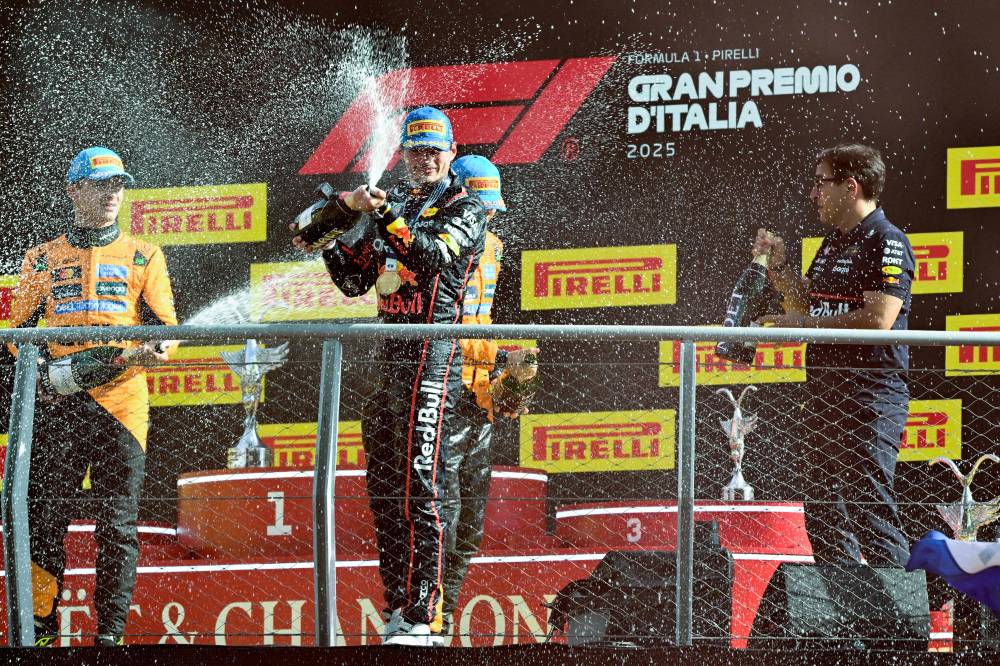 Second placed McLaren's British driver Lando Norris (L), first placed Red Bull Racing's Dutch driver Max Verstappen and Red Bull Racing's Technical Director Pierre Wache (R) celebrate on the podium after the Italian Formula One Grand Prix at the Autodromo Nazionale Monza circuit, in Monza, northern Italy, on September 7, 2025. (Photo by Philippe Lopez / AFP)