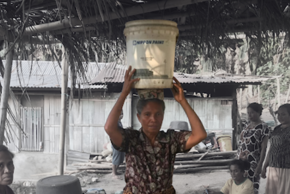 Maria Fatima Bunga while trying to while trying to transport water from Ae Wuka springs for daily needs. Photo by Aliansi Kolibri.