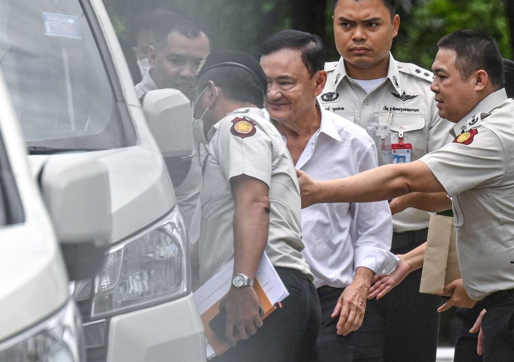 Thailand's former Prime Minister Thaksin Shinawatra (centre) is escorted into a police van outside the Supreme Court in Bangkok after he was sentenced to a year in prison. Photo by Panumas Sanguanwong/THAI NEWS PIX/AFP