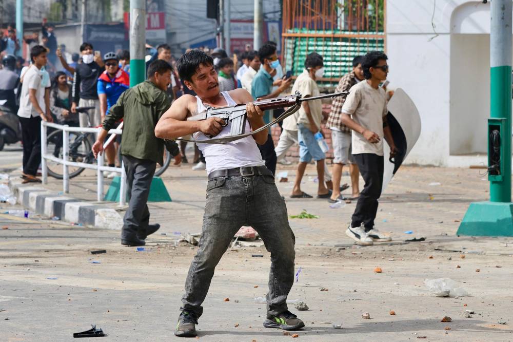 A protester wields a firearm as demonstrators gather outside the Singha Durbar palace complex during a protest to condemn the police's deadly crackdown on demonstrators in Kathmandu on Sept 9, a day after demonstrations over social media prohibitions and corruption by the government. (Photo by Prabin RANABHAT / AFP)