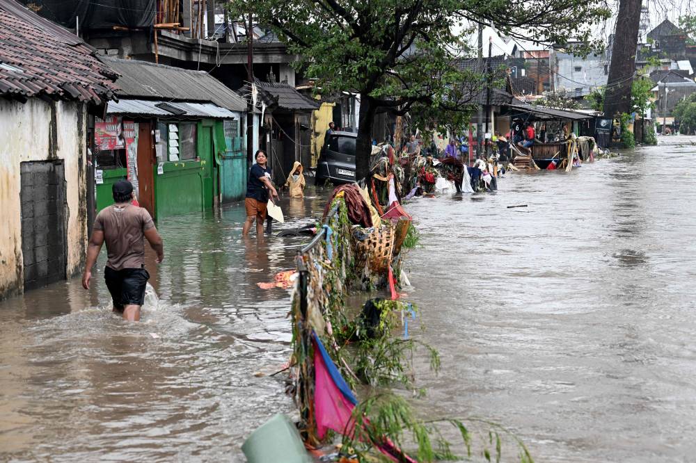 Residents wade through floodwaters in their neighbourhood following heavy rainfall in Denpasar, Indonesia's Bali island. Photo by Sonny Tumbelaka/AFP