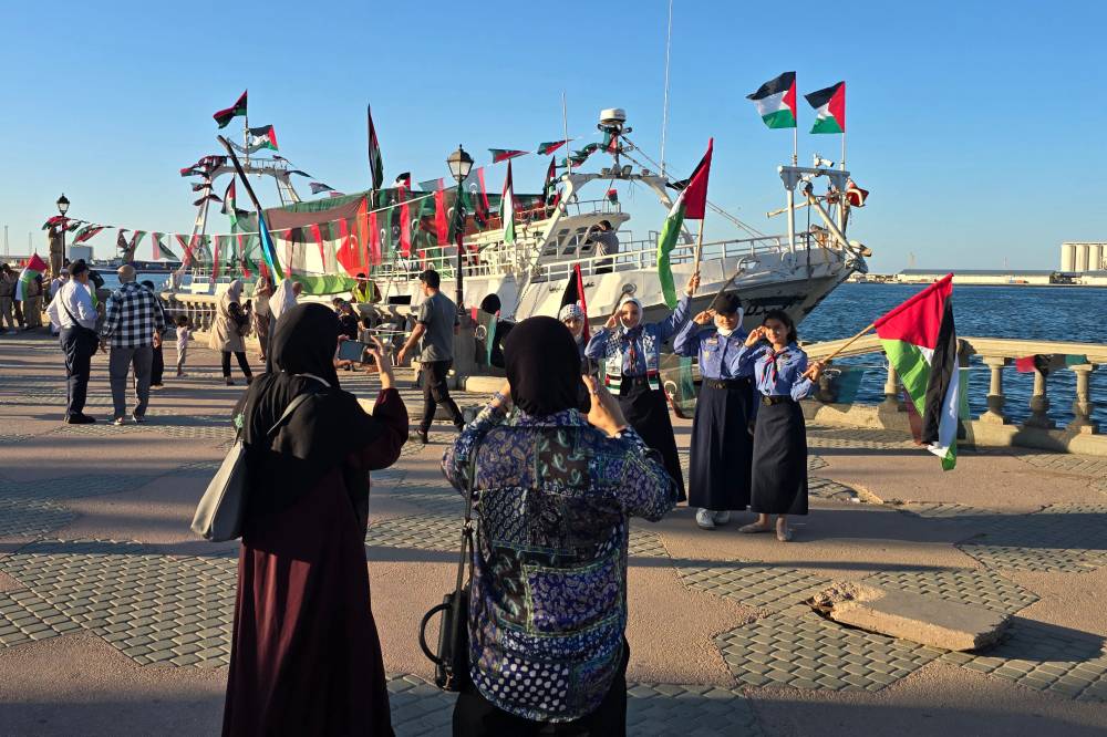 Libyan girl scouts pose for a picture in front of the Omar al-Mukhtar ship, a Libyan ship setting sail on Sept 17, 2025, to join the Global Sumud Flotilla, at the port in Tripoli on Sept 16, 2025. - (Photo by Mahmud Turkia / AFP)