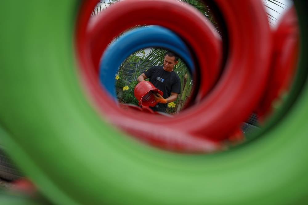 Entrepreneur Muhammad Akhmal inspecting tire-based decorative items being dried, photographed at his workshop in Kampung Pulau, near Durian Tunggal, today.