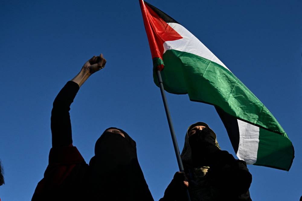 Protesters hold a Palestinian flag as they take part in the 'Stop the Genocide' rally in support of Gaza, at Place de la Republique, in Paris. Photo by AFP