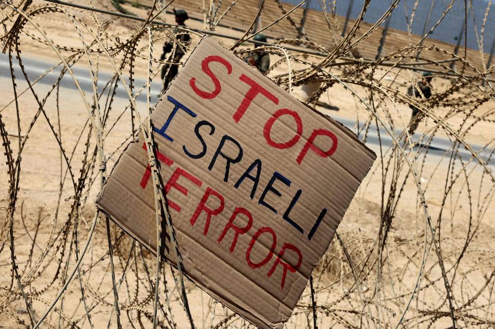A sign placed by left-wing Israeli activists hang along the border with the Gaza Strip after a protest calling for an end to the war between Israel and Hamas, on September 19, 2025, in southern Israel. The Israeli military warned on September 19 that it will operate with "unprecedented force" in Gaza City, urging residents to flee southwards while announcing the closure of a temporary evacuation route opened 48 hours earlier. (Photo by Jack GUEZ / AFP)