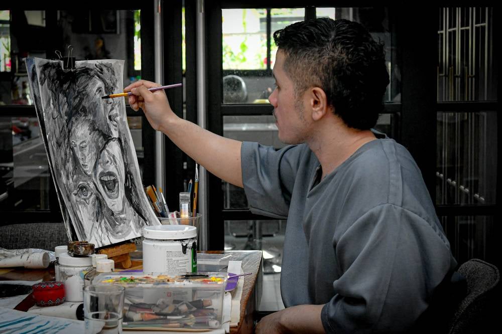 Artist Aiman Zamri, 29, completing his surrealist paintings at his home in Bandar Puteri Klang, recently. Photo by Bernama
