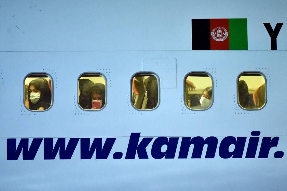 Passengers look out through the windows of a Boeing 737-31S Kam Air passenger plane with people evacuated from Afghanistan on board at Boryspil International Airport outside Kiev, on Aug 23, 2021. - (Photo by SERGEI GAPON / AFP)