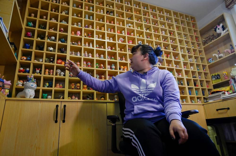 The picture shows music student Wang Zhaoxue showing the "blind box" toys she collected, during an interview at her home in Beijing. The toys, first popularised in Japan, have fixated China in recent years, also driving a booming second-hand market and decorating the desks of white-collar workers and livestreams of box-opening influencers across the country. (Photo by WANG ZHAO / AFP) / TO GO WITH CHINA-ECONOMY-LIFESTYLE-TOYS,FOCUS BY DANNI ZHU AND JING XUAN TENG