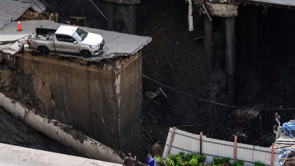 A portion of a busy road in the Thai capital caved in, leaving a massive 50-metre-deep hole in front of a main hospital and forcing people nearby to evacuate. - (Photo by Chanakarn Laosarakham / AFP)