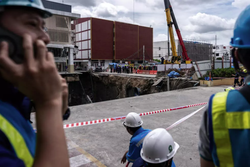 Dozens of police and city officials cordoned off the site, while a pickup truck teetered precariously on the edge of the hole. - (Photo by Chanakarn Laosarakham / AFP)