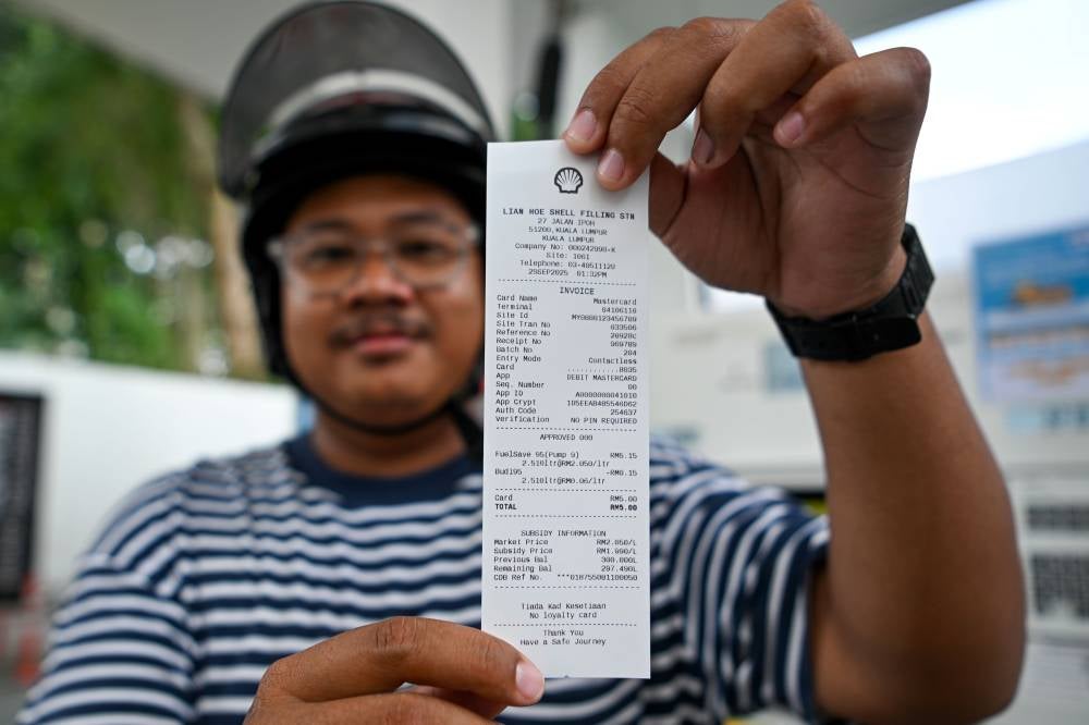 Rahmah Cash Contribution (STR) recipient, Sadiq Sani, after refueling with subsidised Ron95 petrol at RM1.99 per litre. Photo by Bernama