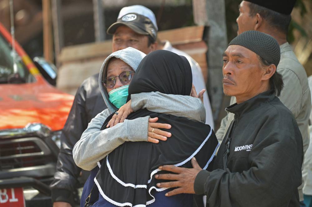 Relatives of missing students embrace as search and rescue operations continue at Al Khoziny Islamic boarding school in Sidoarjo, East Java province, after the multi-storey school building collapsed two days earlier. Photo by Juni Kriswanto/AFP