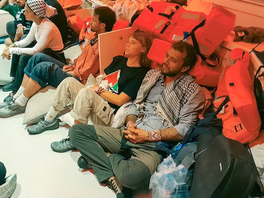 This handout picture released by the Israeli Foreign Ministry shows Swedish climate activist Greta Thunberg (C) and Brazilian activist Thiago Avila (R), along with other activists, after the Israeli navy intercepted the Global Sumud Flotilla carrying humanitarian aid to Gaza on Oct 1, 2025, as stated by the ministry. Israel said on Oct 2 it will deport to Europe pro-Palestinian activists on an aid flotilla headed towards Gaza as the Israeli navy intercepted vessel after vessel in the Mediterranean. The Global Sumud Flotilla of around 45 vessels began its voyage to Gaza last month, with politicians and activists including Thunberg aiming to break Israel's siege of the Palestinian territory, where the United Nations says famine has set in. Photo by Israeli Foreign Ministry/AFP FILE PIX