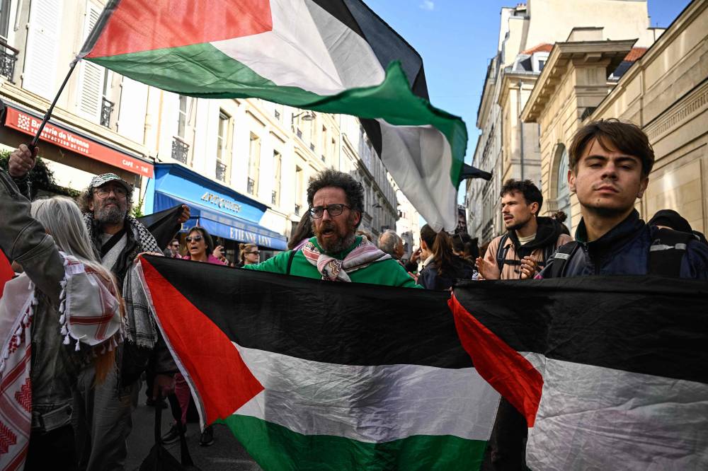 Protesters and relatives of the French nationals who took part in a flotilla carrying pro-Palestinian activists and aid for Gaza and are still detained in Israel march with Palestinian flags towards the Hotel Matignon, the French prime minister's official residence, during a rally in Paris on Oct 5, 2025. - (Photo by JULIEN DE ROSA / AFP)