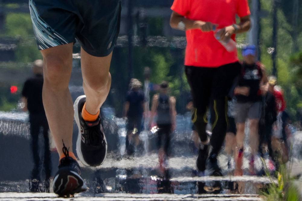 People run on a sidewalk around the Imperial Palace on a hot day in Tokyo on June 28, 2025. (Photo by Kazuhiro NOGI / AFP)