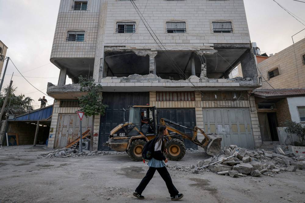 A schoolgirl walks past the destroyed apartment of Ahmad Rafiq al-Haimuni, a detained Palestinian accused of taking part in an operation against Israelis. Photo by Hazem Bader/AFP