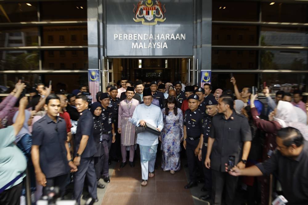 Finance Minister and Prime Minister Datuk Seri Anwar Ibrahim holds up a bag containing Budget documents before heading to Parliament to table the 2026 Budget, today. - Photo by Bernama