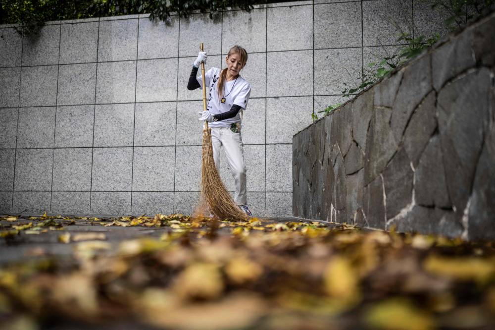 Retired yakuza Mako Nishimura brooms fallen leaves during a cleaning activity with right-wing group members at the Gifu Gokoku shrine in Gifu. Photo by Yuichi Yamazaki/AFP