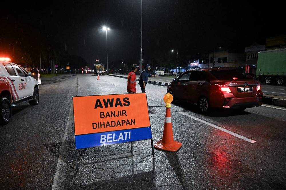 Motorists made their way through flooded areas along Jalan Butterworth-Ipoh, Simpang yesterday. - Photo by Bernama