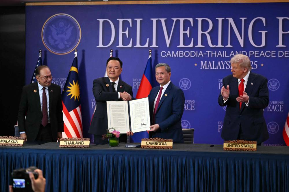 US President Donald Trump (R) claps as Thailand's Prime Minister Anutin Charnvirakul (2nd L) shakes hands with Cambodia's Prime Minister Hun Manet (2nd R) as Malaysia's Prime Minister Anwar Ibrahim during a ceremonial signing of a ceasefire agreement between Cambodia and Thailand on the sidelines of the 47th Association of Southeast Asian Nations (ASEAN) Summit in Kuala Lumpur on October 26, 2025. (Photo by ANDREW CABALLERO-REYNOLDS / AFP)