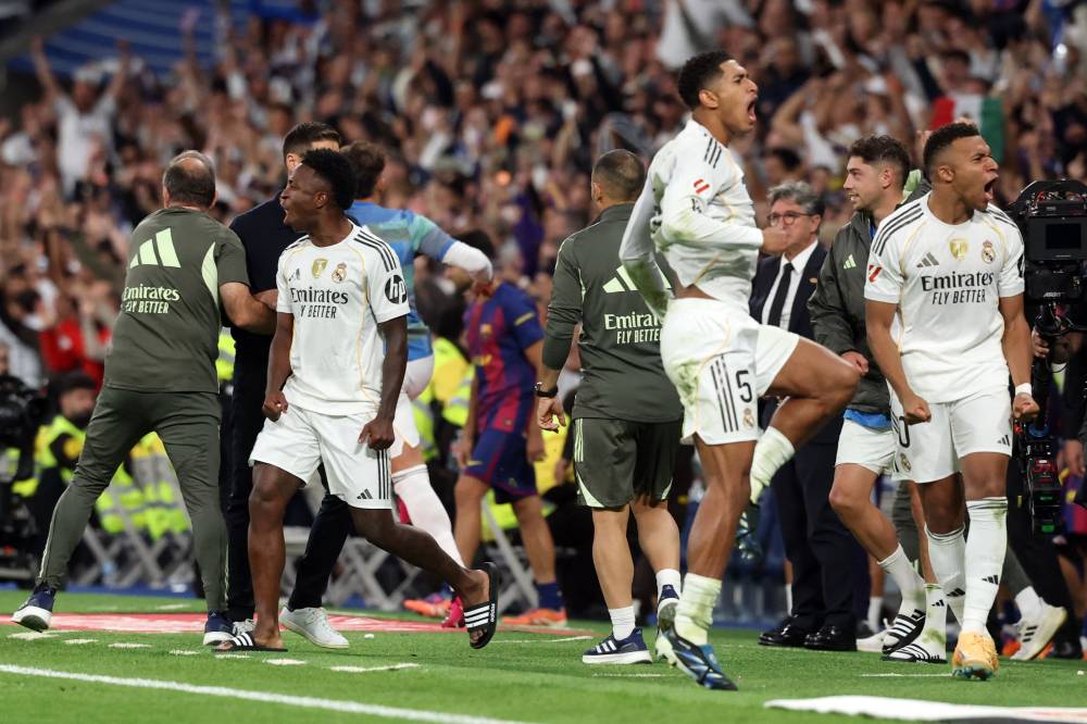 Real Madrid's Brazilian forward Vinicius Junior (L), Real Madrid's English midfielder Jude Bellingham (C) and Real Madrid's French forward Kylian Mbappe celebrate at the end of the Spanish league football match between Real Madrid CF and FC Barcelona at Santiago Bernabeu Stadium in Madrid on October 26 , 2025. (Photo by Oscar DEL POZO / AFP)