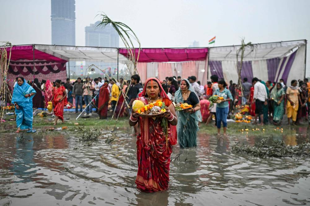 Hindu devotees gather to offer prayers to the Sun god on the occasion of 'Chhath Puja' festival, along the banks of river Yamuna in New Delhi on October 27, 2025. (Photo by Arun SANKAR / AFP)
