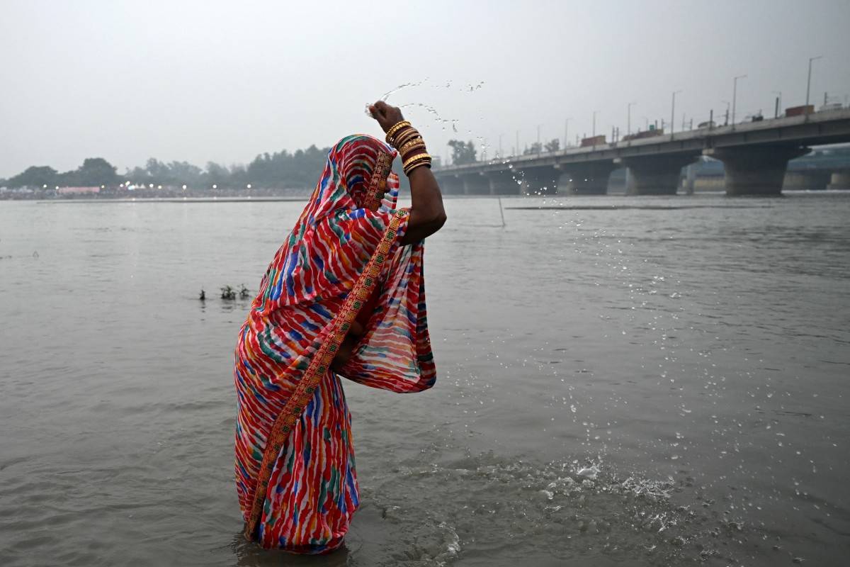 A Hindu devotee gathers to offer prayers on the occasion of the Hindu festival of 'Chhath Puja', on the banks of river Yamuna in New Delhi on October 27, 2025. (Photo by Arun SANKAR / AFP)