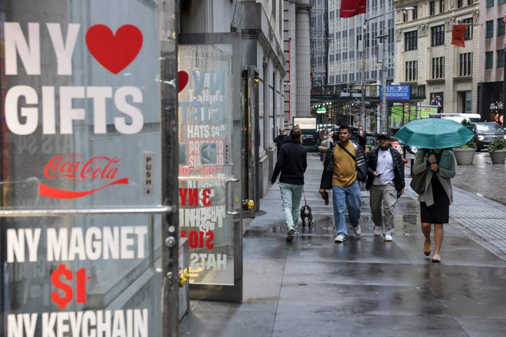 People walk in the rain on Oct 30, 2025 New York City. - (Photo by ANGELA WEISS / AFP)