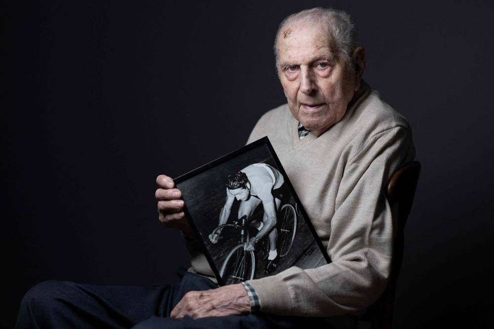 Olympic champion in Men's Team Pursuit in track cycling at the 1948 London Games, Charles Coste, poses with a photo of himself when he was competing during a photo session at home in Bois-Colombes, northwestern of Paris, on Jan 30, 2024. Cycling champions Charles Coste has died on Oct 30, 2025, at the age of 101. - (Photo by JOEL SAGET / AFP)