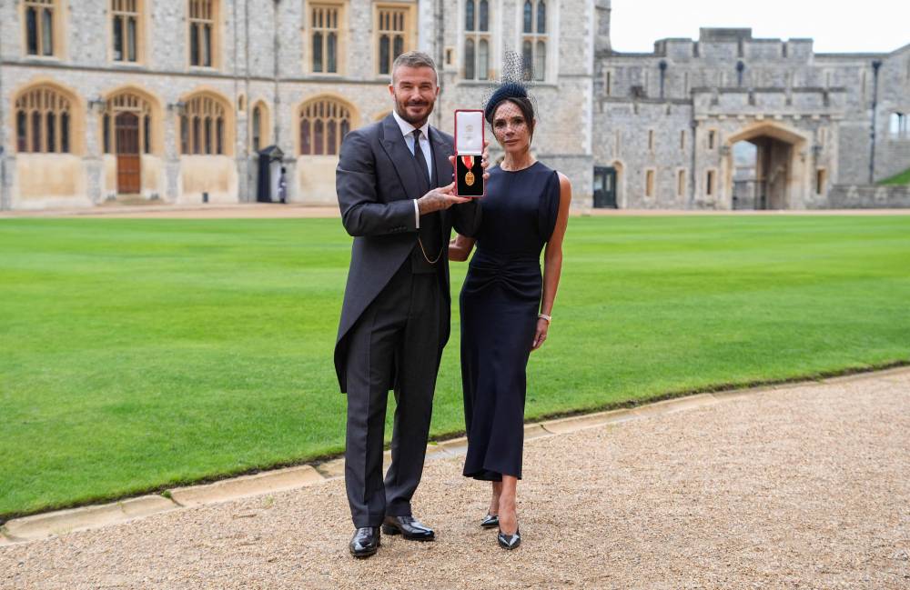 Former England footballer David Beckham (L) poses next to his wife singer and fashion designer Victoria Beckham (R) with his medal after being appointed as a Knight Bachelor (Knighthood) for services to sport and charity at an investiture ceremony at Windsor Castle on November 4, 2025. (Photo by Andrew Matthews / POOL / AFP)