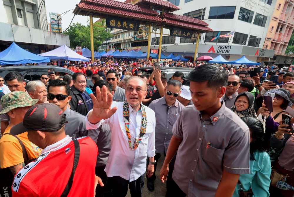Datuk Seri Anwar Ibrahim waves to the crowd during a walkabout session at Tamu Minggu Jalan Gaya on Sunday. - Photo by Bernama