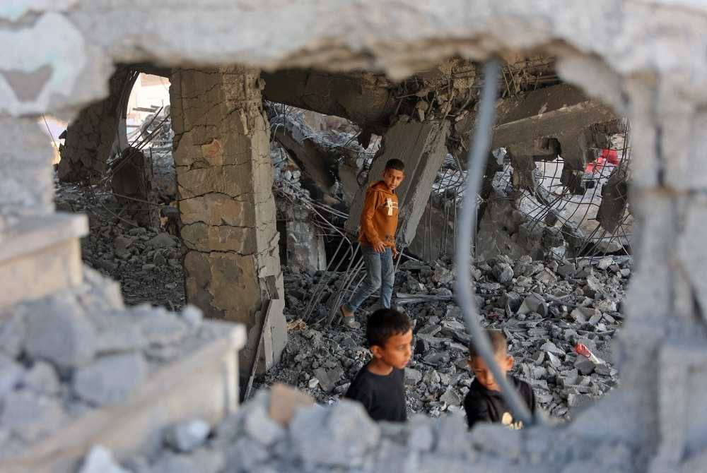Palestinian boys walk amid the debris of a damaged building belonging to the Ministry of Religious Endowments, which was sheltering displaced people in the Zeitoun neighborhood of Gaza City on Nov 20, 2025, a day after it was targeted by Israeli army. - (Photo by Omar AL-QATTAA / AFP)