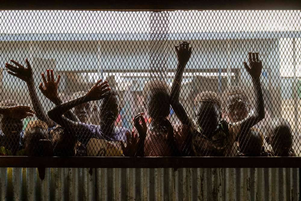 Children gather at the fenced window of a safe-space classroom managed by War Child Holland at the Renk Transit Center in Renk, South Sudan, on Nov 17, 2025. - (Photo by RIAN COPE / AFP)
