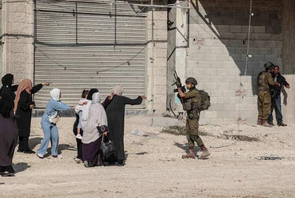 Palestinian women react as Israeli soldiers detain a resident (R) of the Nur Shams refugee camp, near Tulkarem in the Israeli-occupied West Bank, during a protest by residents at the entrance of the camp demanding the right to return to their homes, on Nov 18, 2025. - (Photo by ZAIN JAAFAR / AFP)