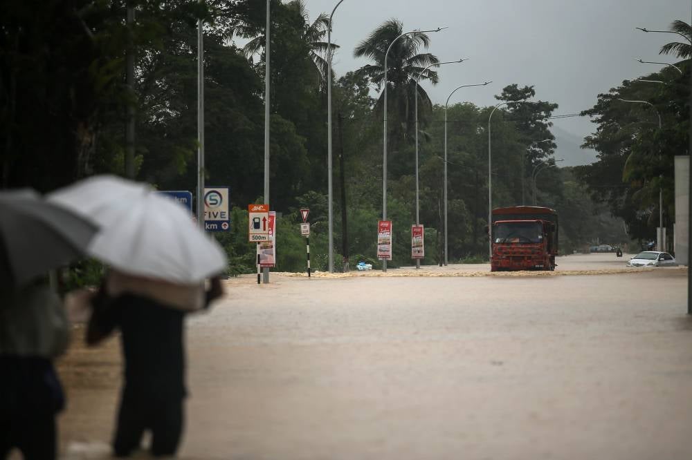 A mother who is seven months pregnant braved 500 metres of thigh-deep floodwaters to flee her home in Kampung Panji after it was inundated. - Photo by Bernama