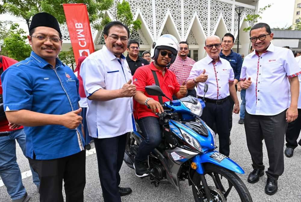 In line with the rider entrepreneurship initiative, CIMB Group chairman Datuk Syed Zaid Albar (two, right) recently presented over 60 motorcycles to gig workers from Kuala Lumpur and Selangor at the Bukit Jalil People's Housing Project. - Photo courtesy of CIMB