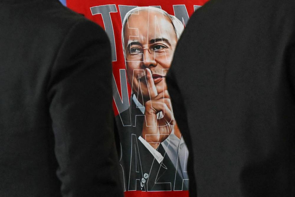 This picture shows a supporter's t-shirt bearing an image of Malaysia's former prime minister Najib Razak hushing, during his 1MDB trial at the Palace of Justice, which houses the Malaysian Court of Appeal and Federal Court, in Putrajaya on December 26, 2025, ahead of the verdict. (Photo by Mohd RASFAN / AFP)