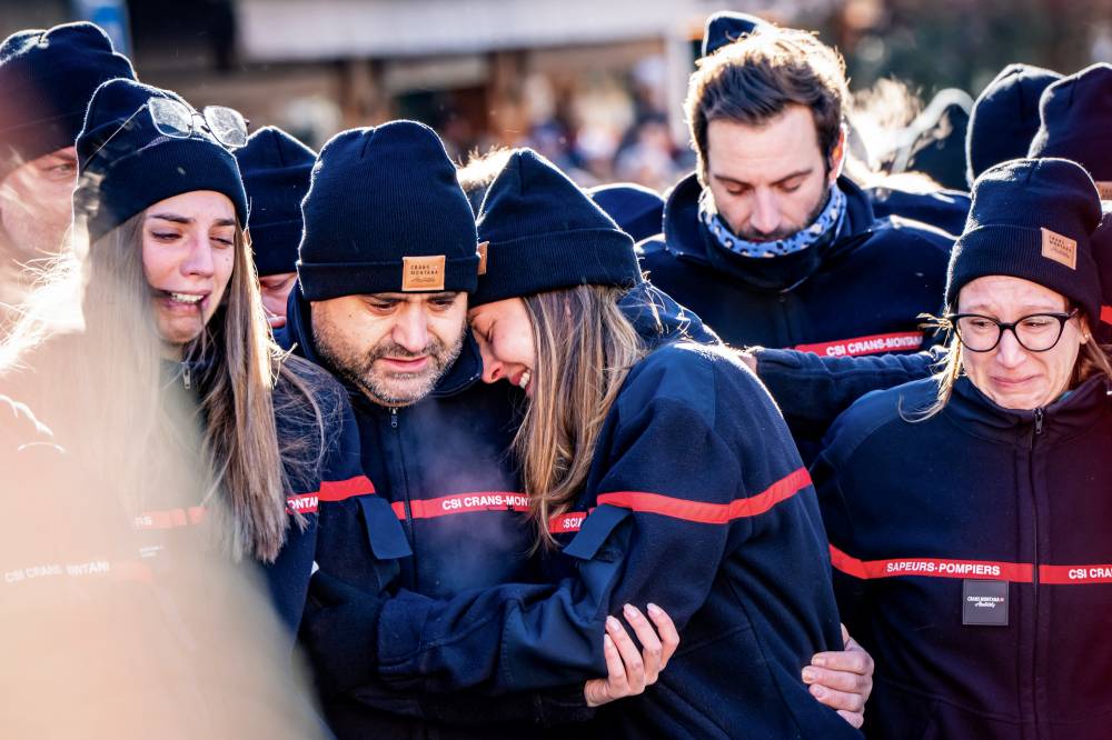 Firefighters from the Municipality of Crans-Montana react as they gather around a makeshift memorial to pay their respects by laying flowers, candles and messages near the Constellation bar, on Jan 4, 2026, in Crans-Montana in honour of the victims of the fire that ripped through the venue in the luxury Alpine ski resort on New Year's Eve. (Photo by MAXIME SCHMID / AFP)
