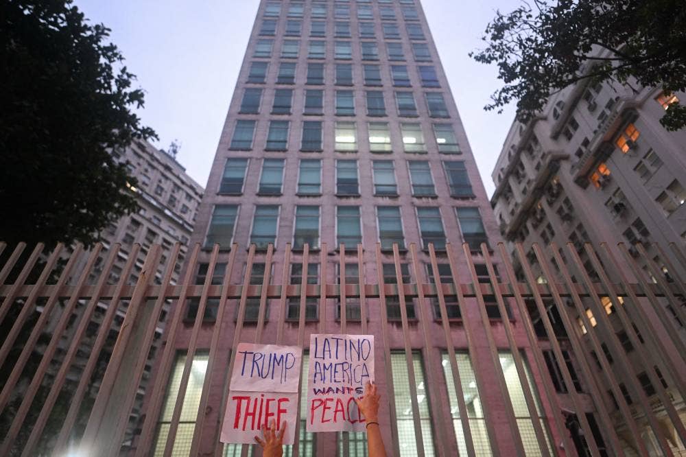 A woman puts up banners against US president Donald Trump on the gates of US Consulate in Rio de Janeiro during a demonstration in support of Venezuela's President Nicolas Maduro at the Cinelandia square in Rio de Janeiro, Brazil on Jan 5, 2026, after US forces captured Venezuelan leader Nicolas Maduro. - (Photo by MAURO PIMENTEL / AFP)