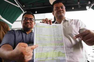 Mohamad Shafiq (right) and Chegubard show a ledger document allegedly containing records of financial transactions involving the receipt of RM1.1 million in cash and luxury assets by a party division chief.