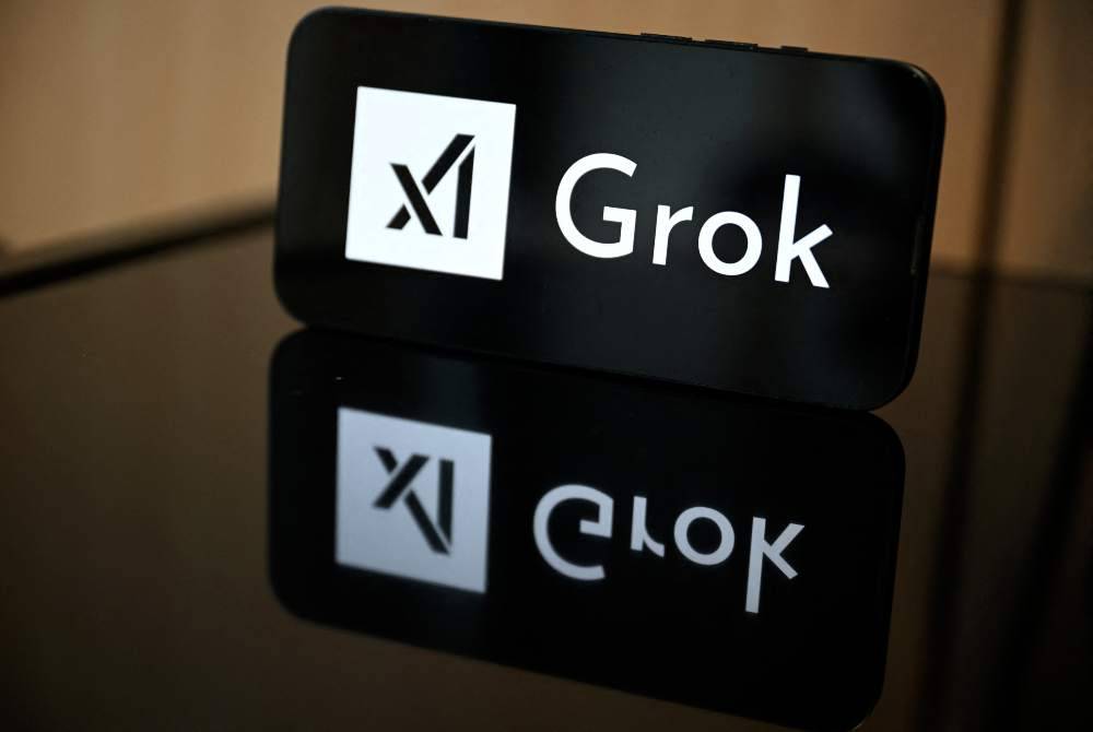 This photograph shows a smartphone bearing the logo of Grok, a generative artificial intelligence chatbot developed by US artificial intelligence company xAI in front of a European Union flag in Brussels on Jan 12, 2026. - (Photo by NICOLAS TUCAT / AFP)