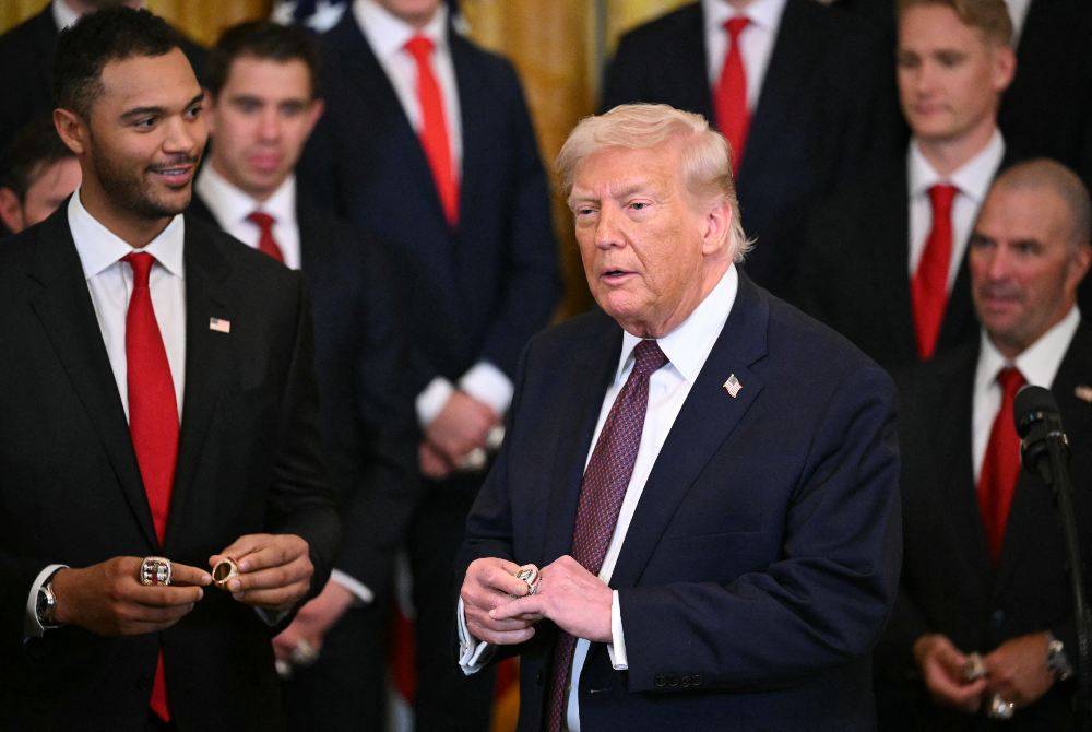 US President Donald Trump tries a champions ring during a congratulatory ceremony with the Florida Panthers of the National Hockey League, winners of the 2025 Stanley Cup, in the East Room of the White House in Washington, DC on Jan 15, 2026. - (Photo by MANDEL NGAN / AFP)