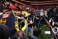 Fans scuffle with security personnel as they storm the field after a penalty decision against Senegal during the Africa Cup of Nations (CAN) final football match between Senegal and Morocco at the Prince Moulay Abdellah Stadium in Rabat on January 18, 2026. (Photo by Franck FIFE / AFP)