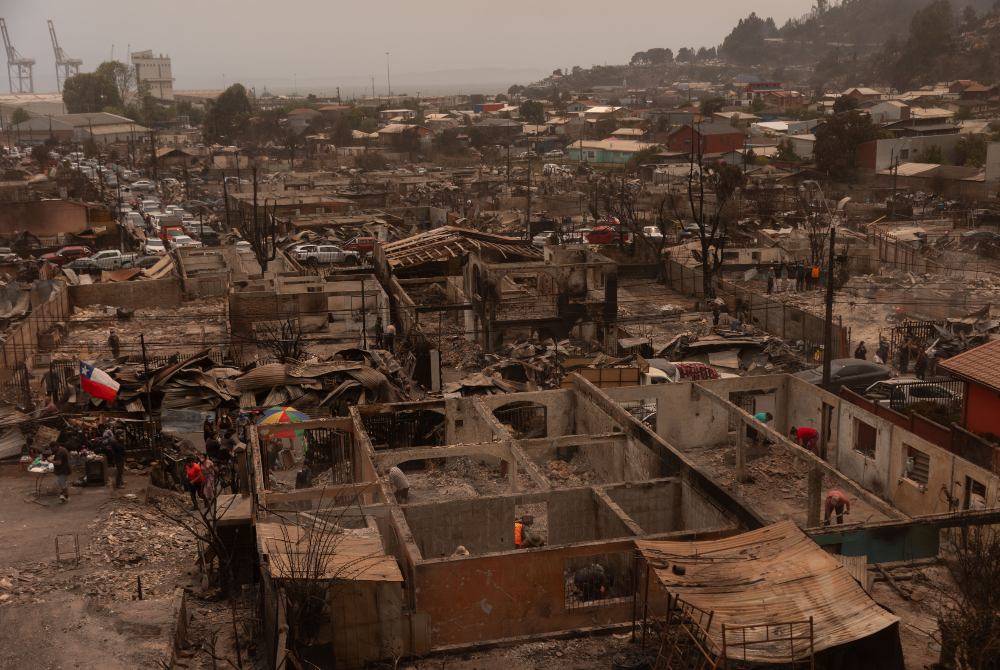 Residents of the Gabriela Mistral neighborhood clear debris from their burnt homes after a wildfire in Lirquen, Chile, on Jan 19, 2026. - (Photo by RAUL BRAVO / AFP)
