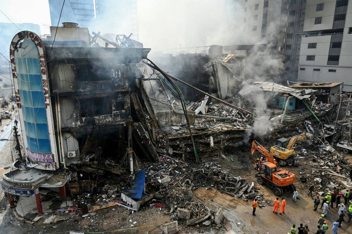 Rescue workers search amid the debris using excavators after a massive fire at a shopping mall in Karachi. Photo by Asif Hassan/AFP
