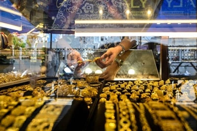 An employee holds pieces of gold jewellery at a jewellery store in Banda Aceh on Jan 14. (Photo by CHAIDEER MAHYUDDIN / AFP)
